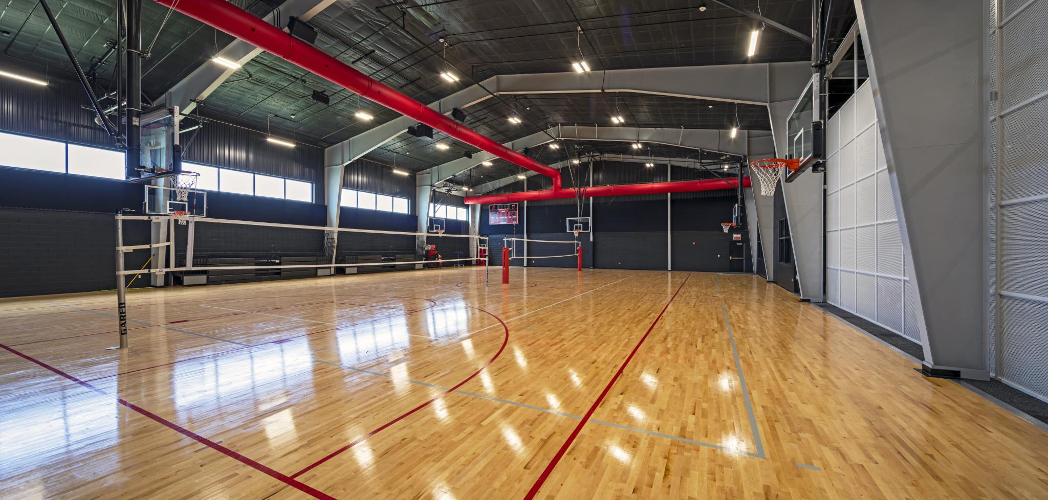 a gymnasium with basketball hops and volleyball nets